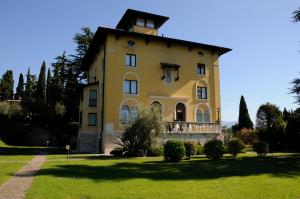 a large yellow building with a balcony on a grass field at Villa Maria Callas Sirmione in Sirmione