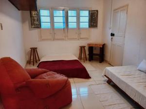 a living room with a red chair and a couch at Casa da Áfrika - Suíte Primavera in Itanhandu