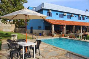 a table with an umbrella next to a swimming pool at Hotel Pousada Caminho Pireneus in Pirenópolis