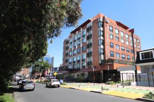 Un edificio en una calle de la ciudad con coches circulando por la calle. en Lancaster House, en Bogotá