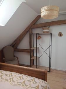 a attic room with a chair and a shelf at Le Gîte Marguerite in Colleville
