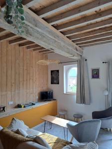 a living room with wooden ceilings and a table and chairs at Le Gîte Marguerite in Colleville