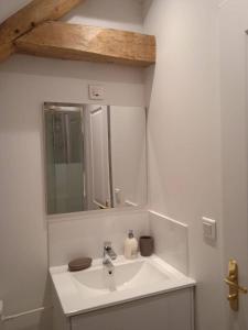 a white bathroom with a sink and a mirror at Le Gîte Marguerite in Colleville +24 photos