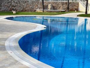 a swimming pool with blue water in a park at Bahia Park Résidence in Cullera