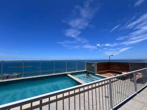 a swimming pool on a building with the ocean in the background at Apart Moderno Proximo ao Mar in Vila Velha