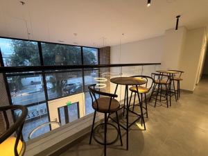 eine Reihe von Tischen und Stühlen in einem Zimmer mit einem großen Fenster in der Unterkunft Apartasuite Smart cerca de la Fundación Santa Fé in Bogotá