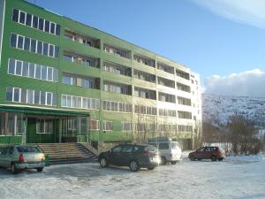 a large green building with cars parked in a parking lot at Khibiny Hotel in Kirovsk