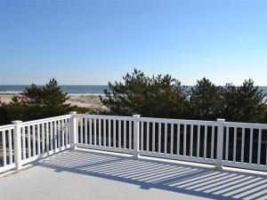 una cerca blanca en la playa cerca del océano en Single Family, Ocean Block, Wifi, Washer And Dryer, Second 2Nd Home From The Ocean! 2Nd From Ocean Contemporary Ship Bottom Home 14010, en Ship Bottom