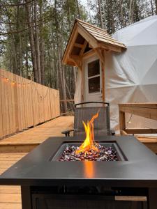 a fire pit on a deck with a tent at The Bonne Chere at New Frontiers Retreat in Eganville