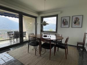una sala da pranzo con tavolo, sedie e finestre di Casa Ai Lupi with Panoramic view a Gordola