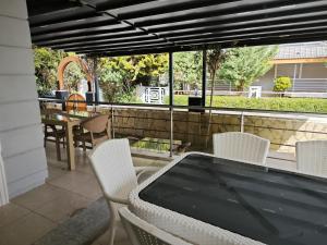 a patio with white chairs and a table with a view of a yard at Adakonak Urla in Urla