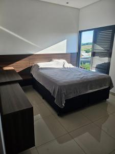 une chambre avec un lit et une grande fenêtre dans l'établissement Recanto Rio Grande, à São João Batista do Glória