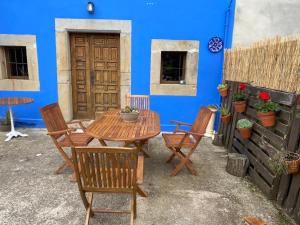 a patio with a wooden table and chairs in front of a blue wall at La Fontanina de Mario in Villaviciosa