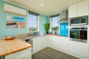 a kitchen with white cabinets and blue walls at Classic Charm, Sea & Mountain Views, Family Fun - KK95170 in Kaikoura