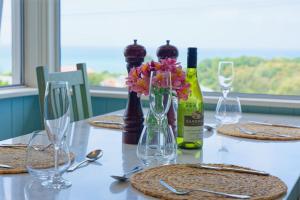 a table with a bottle of wine and flowers on it at Classic Charm, Sea & Mountain Views, Family Fun - KK95170 in Kaikoura +15 photos