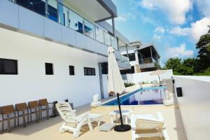 a patio with chairs and an umbrella next to a swimming pool at JJY Apartment in Nadi