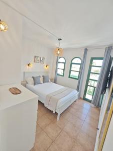 ein weißes Schlafzimmer mit einem weißen Bett und einigen Fenstern in der Unterkunft Paradise Tropical Sun Maspalomas in San Bartolomé de Tirajana