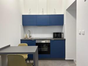 a kitchen with blue cabinets and a table and chairs at NMG APARTMAN - Jogász utca in Pécs