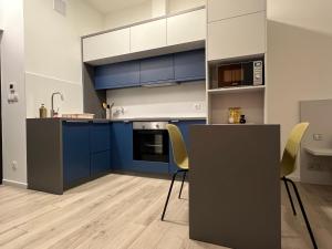 a kitchen with blue cabinets and yellow chairs at J2 Apartman in Pécs +8 photos