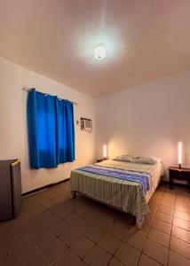 a bedroom with a bed and a blue curtain at Pousada PARAMBUCO in Tamandaré