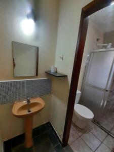a bathroom with a sink and a toilet and a mirror at Pousada Atobá Bertioga in Bertioga