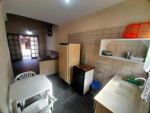 a small kitchen with a refrigerator and a table at Pousada Atobá Bertioga in Bertioga