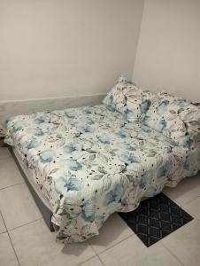 a bed with a blue and white blanket on it at La Ponderosa Studio Apartment in Bogotá