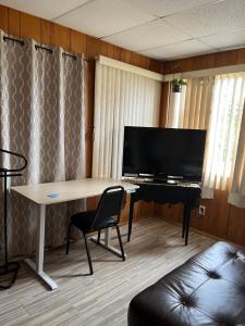 a room with a desk with a piano and a television at Happy Rest Stop House in North Fort Myers