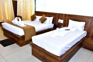 two beds in a hotel room with towels on them at River Valley Retreat Coorg in Madikeri