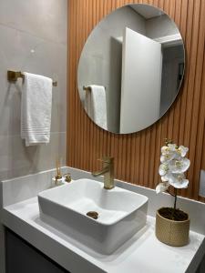 a bathroom with a white sink and a mirror at Flat Premium -Acesso a pé ao shopping Center vale - Edifício Summit (Ar condicionado) in São José dos Campos
