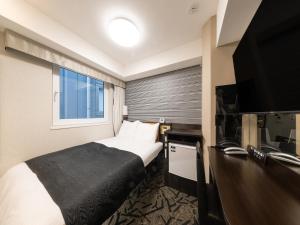 a hotel room with a bed and a flat screen tv at APA Hotel Shibuya Dogenzakaue in Tokyo