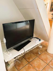 un téléviseur à écran plat posé sur un support blanc dans l'établissement Le Mazet de la Sauvagine, à Saintes-Maries-de-la-Mer