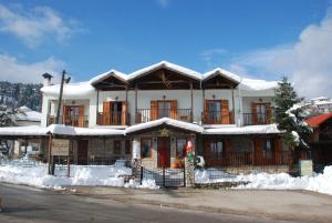 una grande casa con la neve sul davanti di Hotel Antigoni a Neo Chorio
