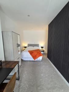 a bedroom with a bed with an orange blanket on it at Spacious New Studio in Blackburn Town Centre in Blackburn