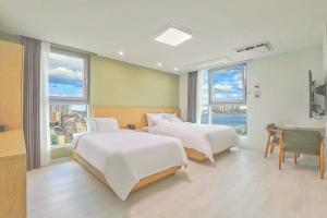 束草市Berith Hotel的一间卧室设有两张床、一张桌子和窗户。