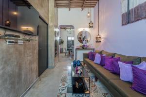 a living room with a brown couch and purple pillows at Casa Lila in Mérida