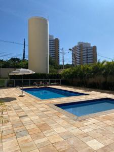 una piscina con sombrilla y un edificio en Apartamento Novo em Londrina, en Londrina