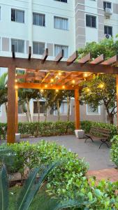 pérgola de madera con banco frente a un edificio en Apartamento Novo em Londrina, en Londrina