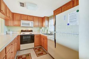a kitchen with wooden cabinets and a white refrigerator at Oceanview Amelia South Condo in Fernandina Beach