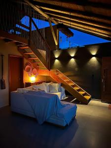 a bedroom with a large bed and a staircase at Garden Guest House Garopaba in Garopaba