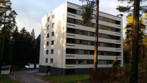 a tall white building with trees in front of it at Nasta Apartment in Nastola
