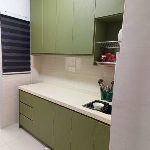 eine Küche mit grünen Schränken und einer Arbeitsplatte in der Unterkunft Rania Homestay Sensory in Kajang