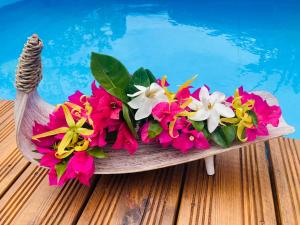 a wooden bowl filled with flowers next to a swimming pool at Noa Noa Lodge in Motu Tiahura