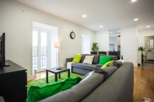 a living room with a gray couch and green pillows at Breathtaking River View in Alfama in Lisbon