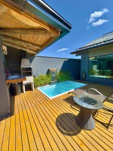 a wooden deck with a table and a swimming pool at Garden Guest House Garopaba in Garopaba