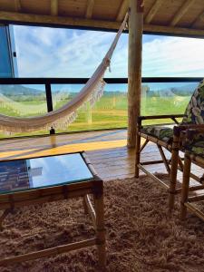 a room with a hammock and a table and a window at Garden Guest House Garopaba in Garopaba +75 photos