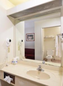 a bathroom with a sink and a large mirror at Comfort Crest Inn Smackover in Smackover