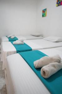 three beds in a room with towels on them at Rivera Hostel in Santa Marta