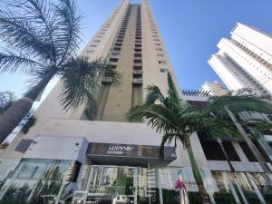 a tall building with palm trees in front of it at iFlat Winner Sport Life Jardim Goiás in Goiânia