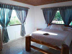 a bedroom with a bed and two large windows at House Villa Las Marias in Juan de Acosta
